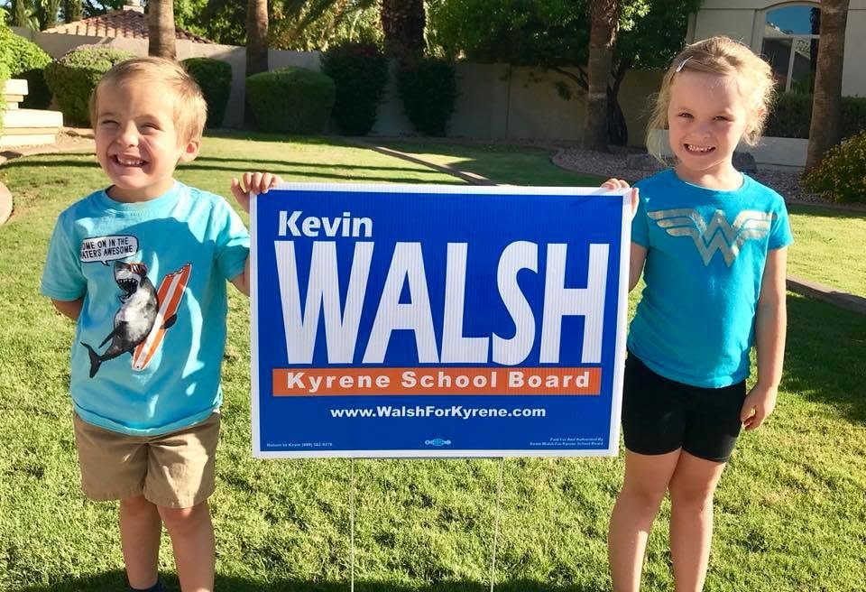 Two young kids holding a Kevin Walsh campaign sign